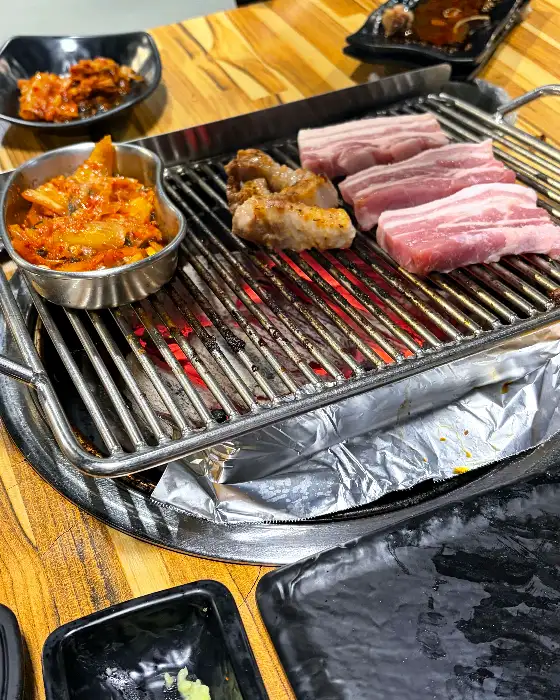 다양하게 차려진 낭만돼지 밑반찬과 숯불 위 고기