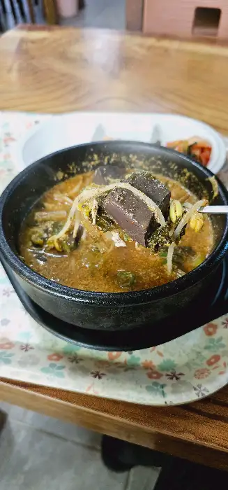 선지해장국 뚝배기에서 숟가락으로 선지와 국물을 떠 올리고 있습니다.