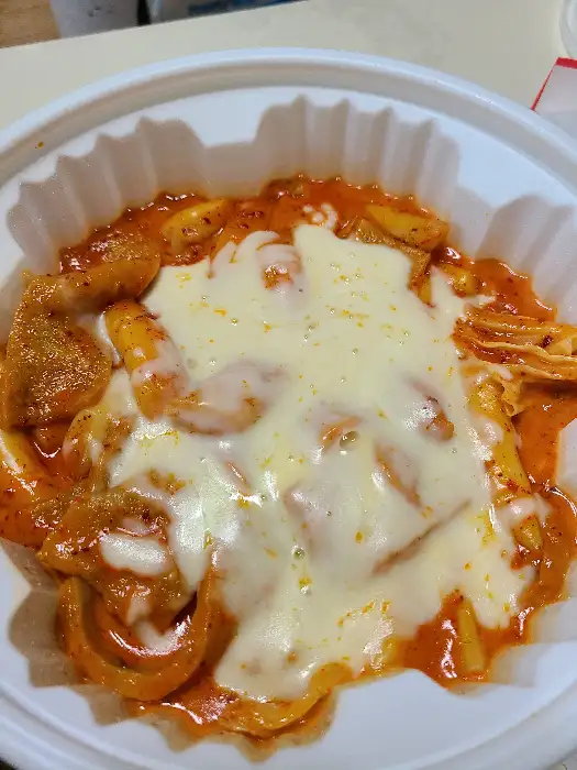 빨간 떡볶이 위에 녹아내린 치즈가 덮인 모습