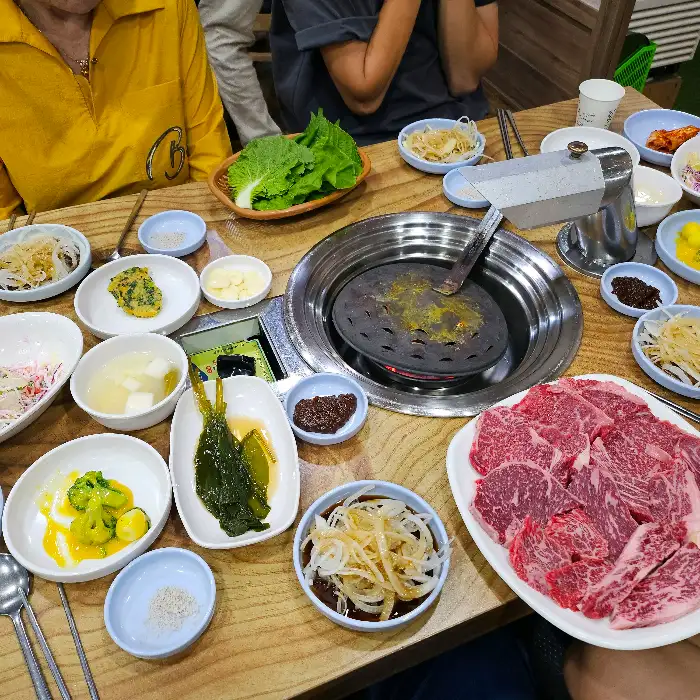 테이블 세팅과 숯불 그릴, 신선한 고기가 놓인 모습