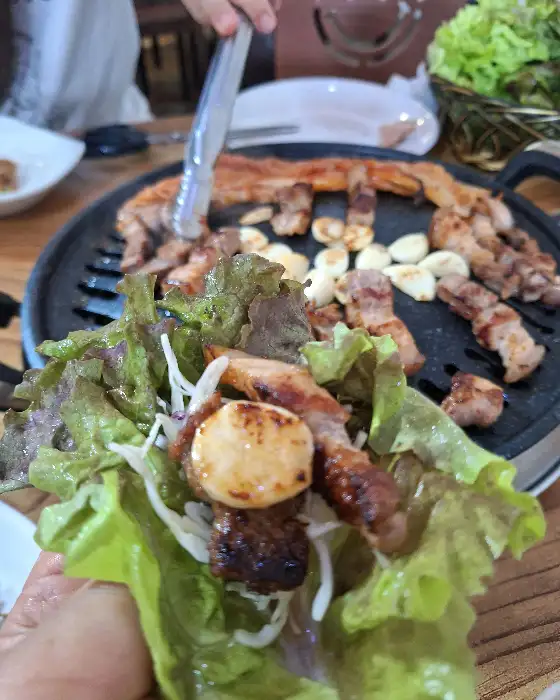상추쌈에 고기와 마늘, 쌈장을 넣어 싸 먹는 모습
