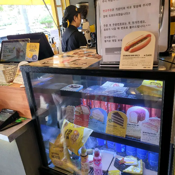 메가커피 모델 사진과 진열된 디저트