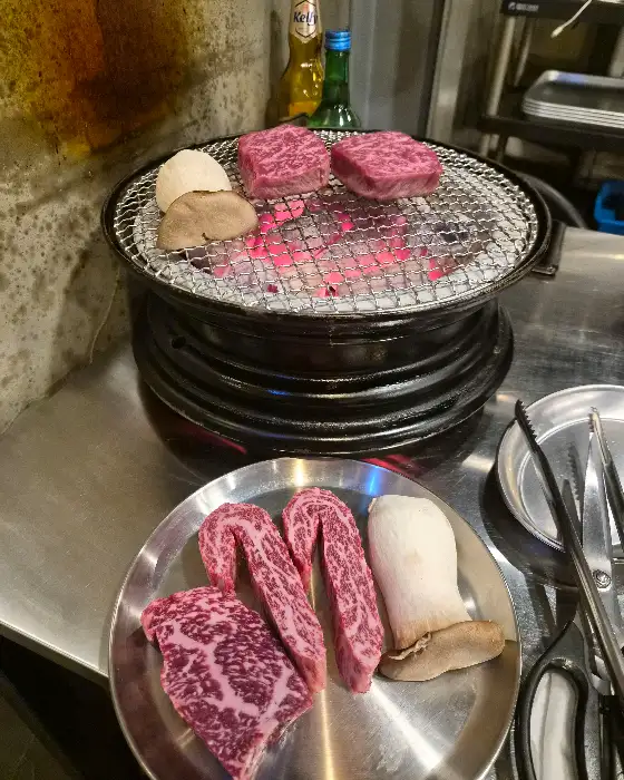구워질 준비가 된 소고기와 버섯, 숯불