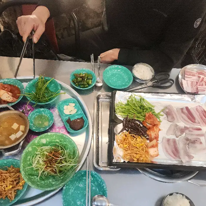 고기, 김치, 콩나물, 미나리 등이 불판 위에서 익고 있는 모습