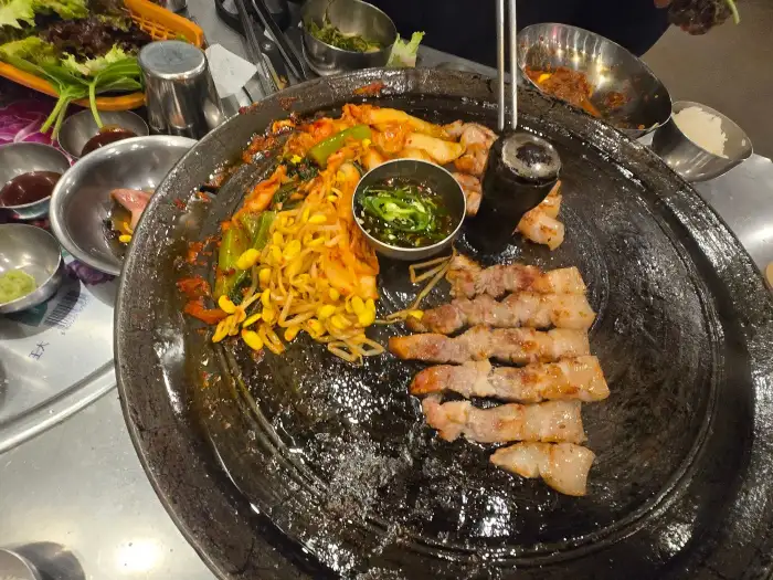 잘 구워진 삼겹살과 곁들임 메뉴가 함께 담긴 모습