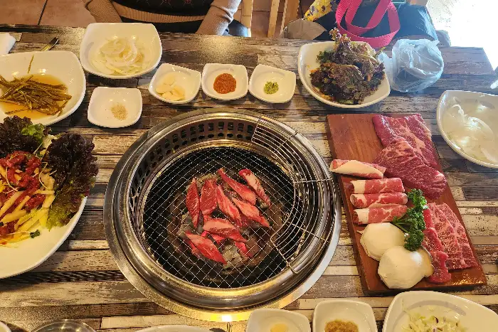 숯불 위에 올라간 돼지갈비와 다양한 반찬들