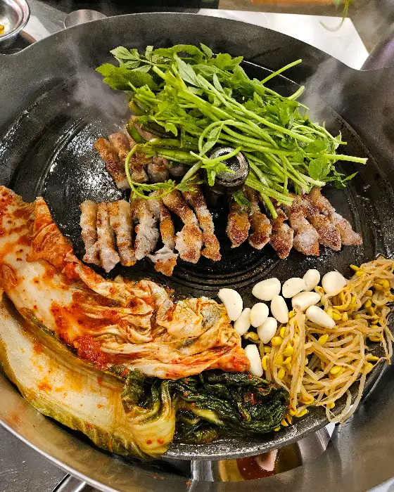 다양한 곁들임 메뉴와 함께 놓인 잘 구워진 삼겹살