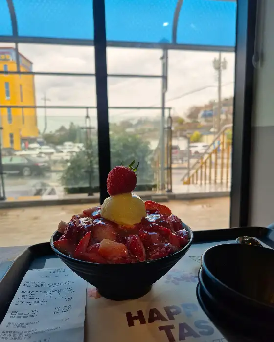 생딸기 빙수 클로즈업. 뽀얀 우유 얼음 위에 싱싱한 생딸기와 찹쌀떡, 아이스크림이 올려져 먹음직스럽습니다.