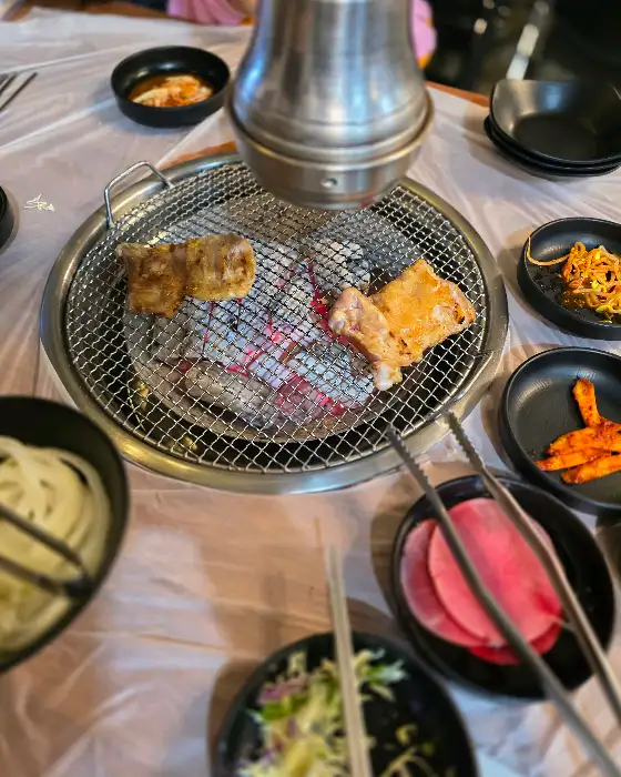 숯불 위에서 익어가는 닭갈비와 곁들임 메뉴