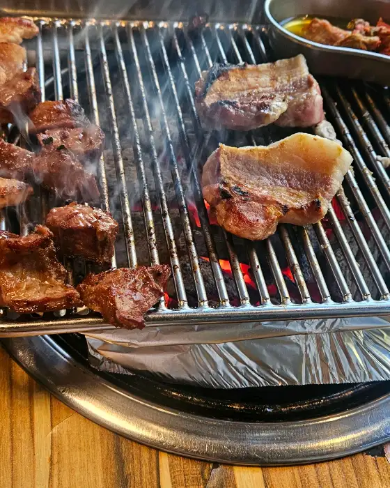 숯불 위에서 맛있게 익어가는 삼겹살과 갈매기살