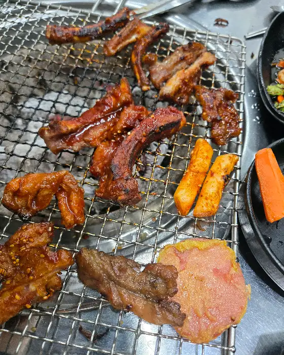 숯불 위에서 구워지는 다양한 쪽갈비와 곁들임 메뉴