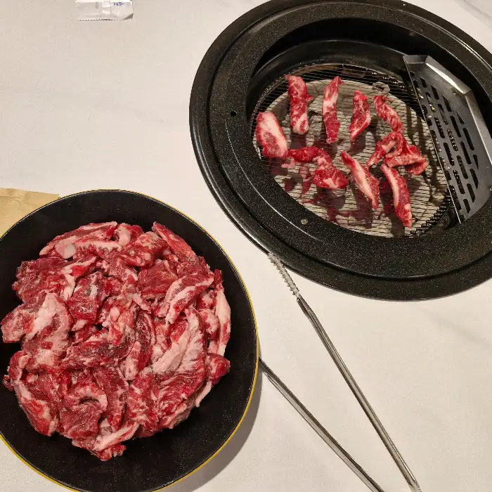 한쪽에는 갓 나온 생갈비살, 다른 한쪽에는 숯불에 구워지고 있는 고기