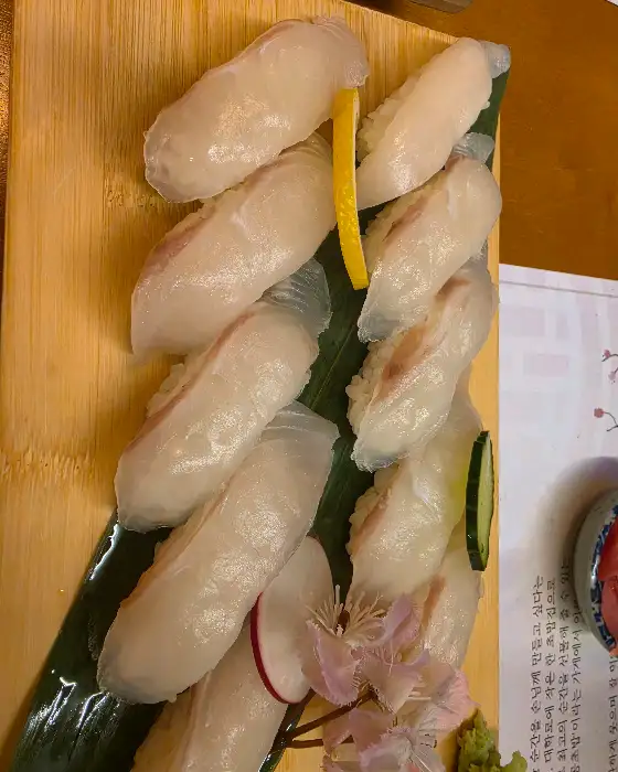 나무 접시에 가지런히 담긴 흰 살 생선 초밥