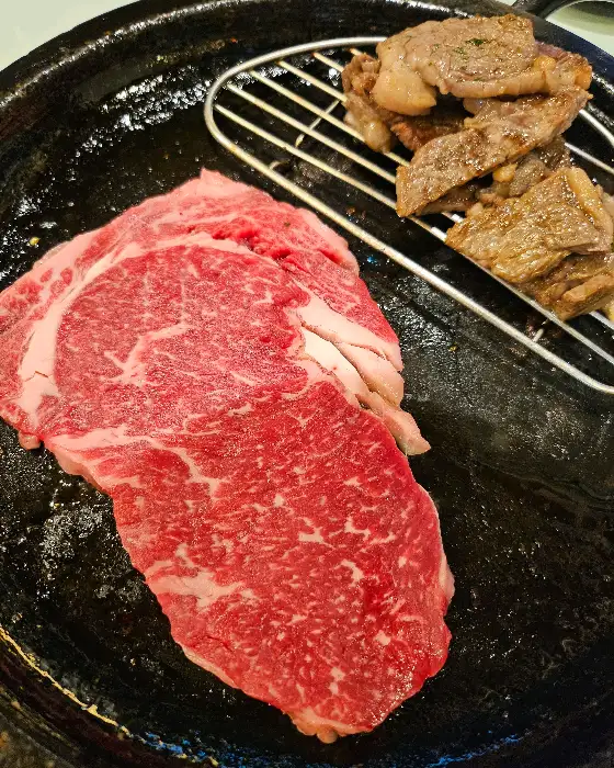 돌판에 올라간 한우와 익어가는 고기 조각들이 보입니다.