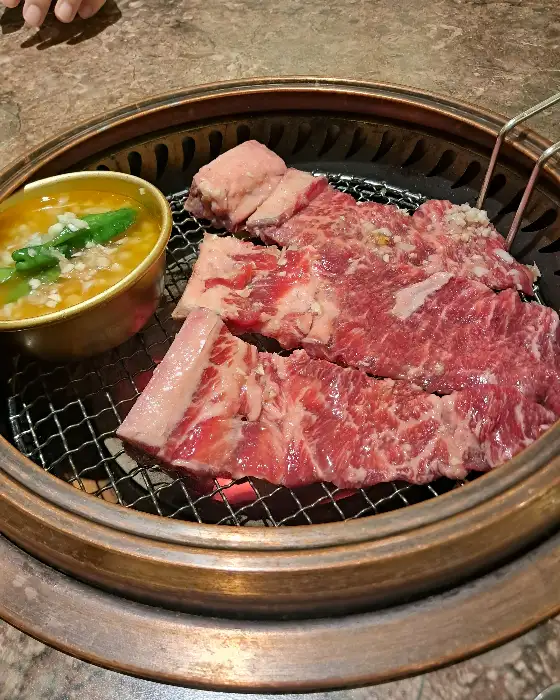 불판 위에서 익어가는 육회와 곁들임 채소