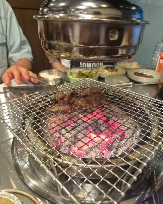 숯불 위에서 익어가는 고기와 곁들임 메뉴