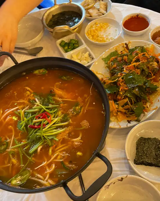 넓은 접시에 신선한 막회가 담겨 있고, 주변에는 쌈 채소, 김, 콩가루, 다진 마늘, 고추, 쌈장 등이 가지런히 준비되어 있다.