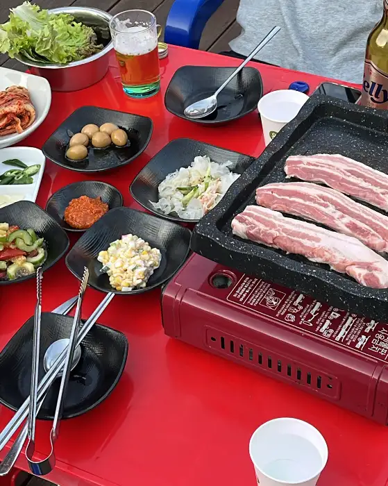 테이블에 차려진 다양한 밑반찬과 삼겹살