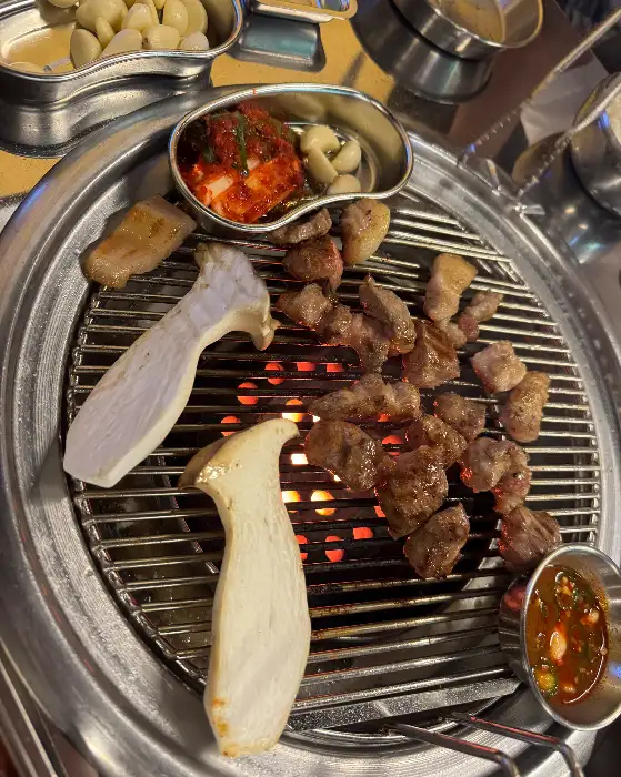 숯불 위에서 구워지는 고기와 버섯