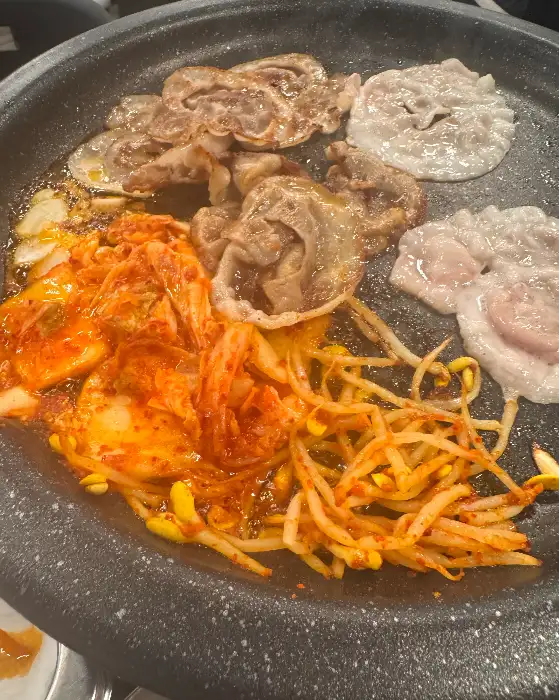 김치와 콩나물무침 위에서 지글지글 익어가는 고기