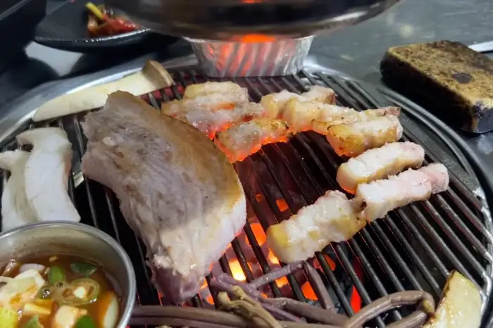 불판 위 고기와 함께 놓인 곁들임 찬들