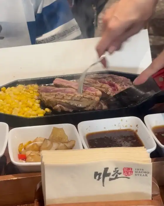 철판 위에 지글거리는 립아이 스테이크와 옥수수