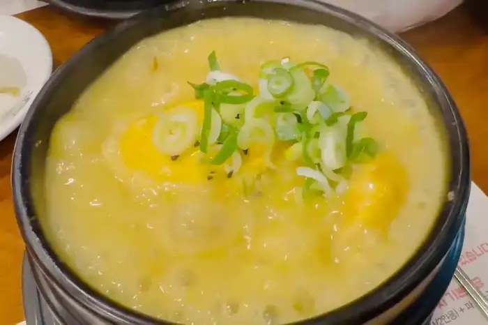 상황 삼계탕의 모습, 걸쭉한 황금빛 국물에 닭 한 마리가 담겨 있다.