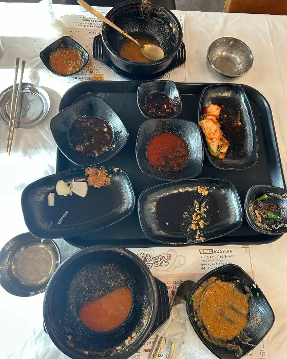 테이블 위에 놓인 정갈한 밑반찬과 흑염소탕의 흔적