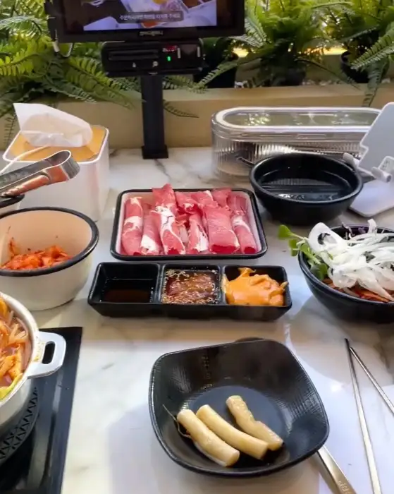 신선한 채소와 얇게 썬 소고기, 다양한 소스가 담긴 테이블 세팅