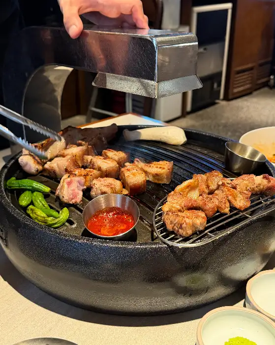 잘 구워진 고기를 집는 집게와 소스가 담긴 그릇