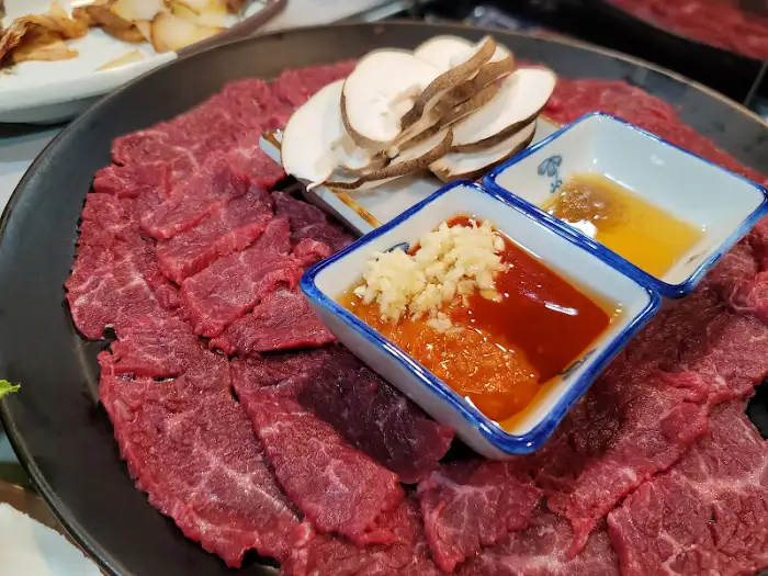 얇게 썬 소고기와 버섯, 마늘, 소스가 담긴 접시