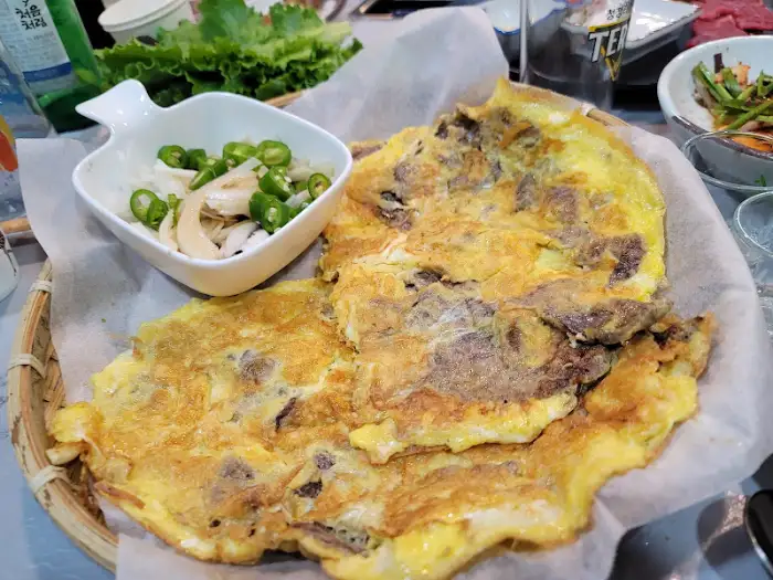 큰 접시에 담긴 계란말이 같은 음식과 곁들임 채소