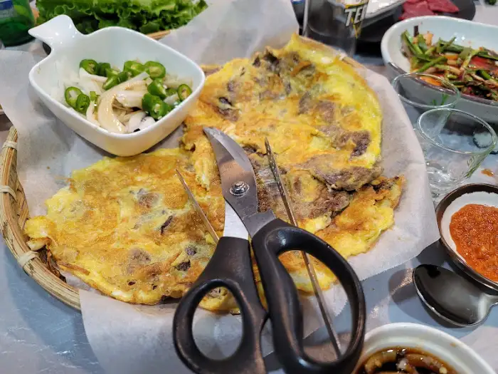 계란말이처럼 보이는 음식과 풋고추, 양파가 담긴 그릇