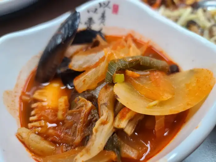 새빨간 국물에 양파, 버섯, 조개살 등 건더기가 푸짐하게 들어있는 짬뽕 또는 울면 같은 중식 요리
