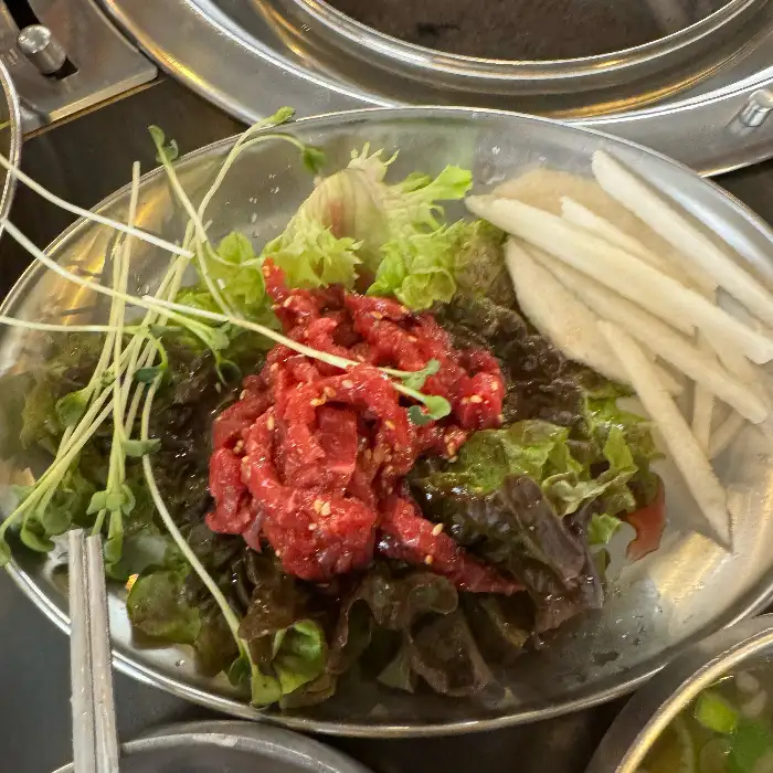 다양한 쌈 채소와 신선한 육회가 담긴 접시