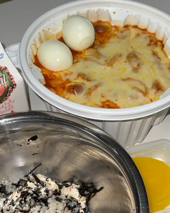 치즈가 녹아내린 떡볶이 위에 계란 두 개가 올라간 모습