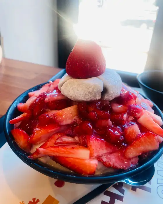 다른 각도에서 본 생딸기 빙수. 빙수 위에 꼼꼼하게 썰어진 딸기 조각들과 찹쌀떡, 아이스크림이 올려져 있습니다.