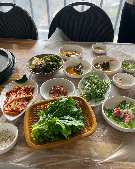 테이블 위에 차려진 다양한 밑반찬과 쌈 채소