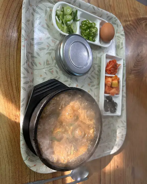 선지해장국 뚝배기와 밥, 그리고 날달걀이 담긴 접시가 보입니다.