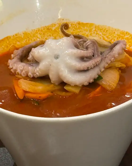 빨간 짬뽕 국물 위에 통통한 낙지 한 마리가 올려져 있다.