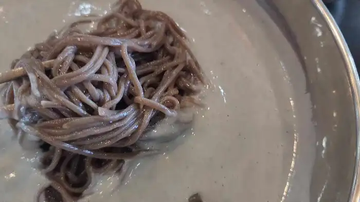 메밀면을 젓가락으로 집어 올리는 모습