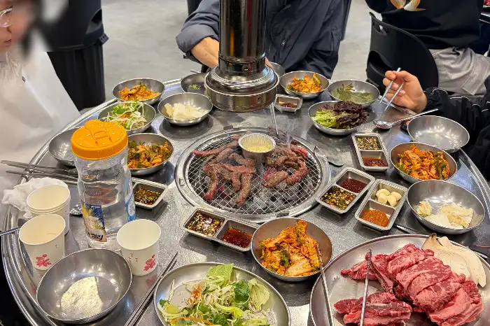 숯불 위에서 구워지고 있는 다양한 고기와 반찬들