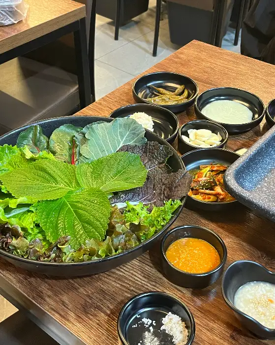 오리 주물럭을 쌈에 싸서 먹는 모습