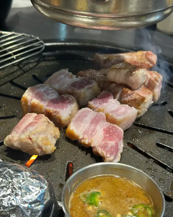 두툼하게 썰린 삼겹살이 불판 위에서 굽히고 있는 모습