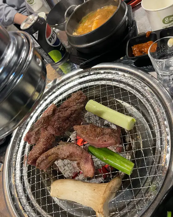 숯불 위에서 익어가고 있는 고기와 곁들임 채소