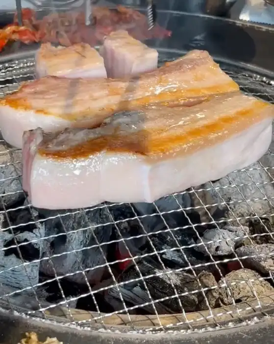두툼한 오겹살이 숯불 위에서 익어가고 있는 모습