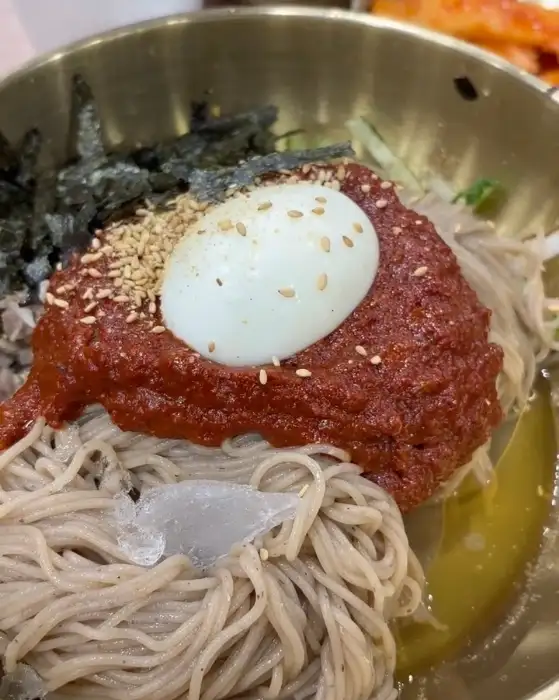 매콤한 양념과 메밀면, 계란 고명이 올라간 비빔막국수 한 그릇