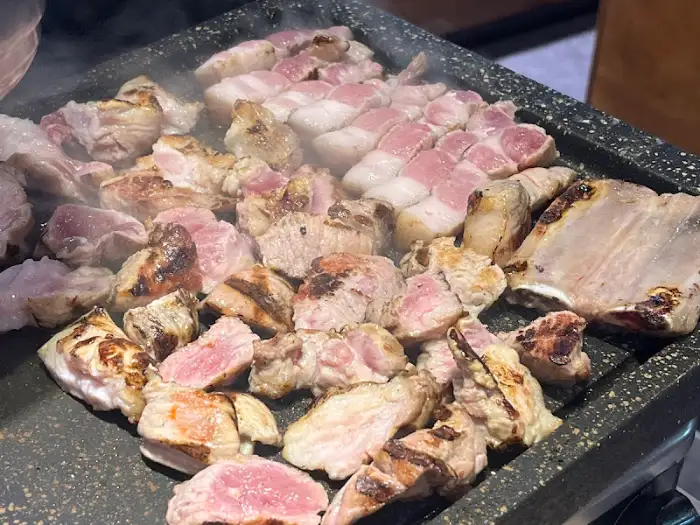 불판 위에서 구워지는 다양한 부위의 돼지고기
