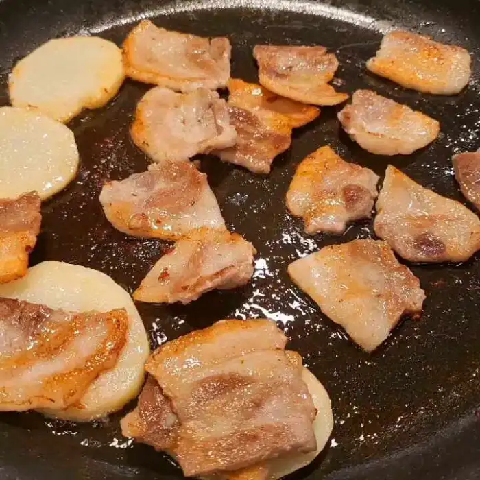 불판 위에서 노릇하게 구워지는 삼겹살과 감자
