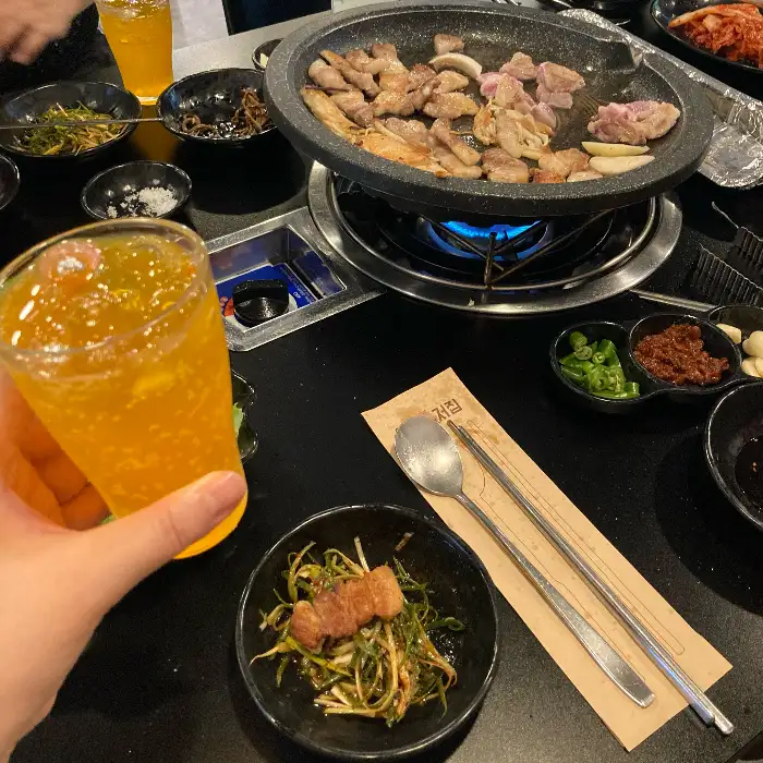 식탁 위에 차려진 푸짐한 고기 구이와 곁들임 반찬, 음료